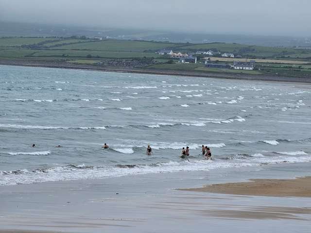 A group of dippers entering the water on the main beach with tiny waves